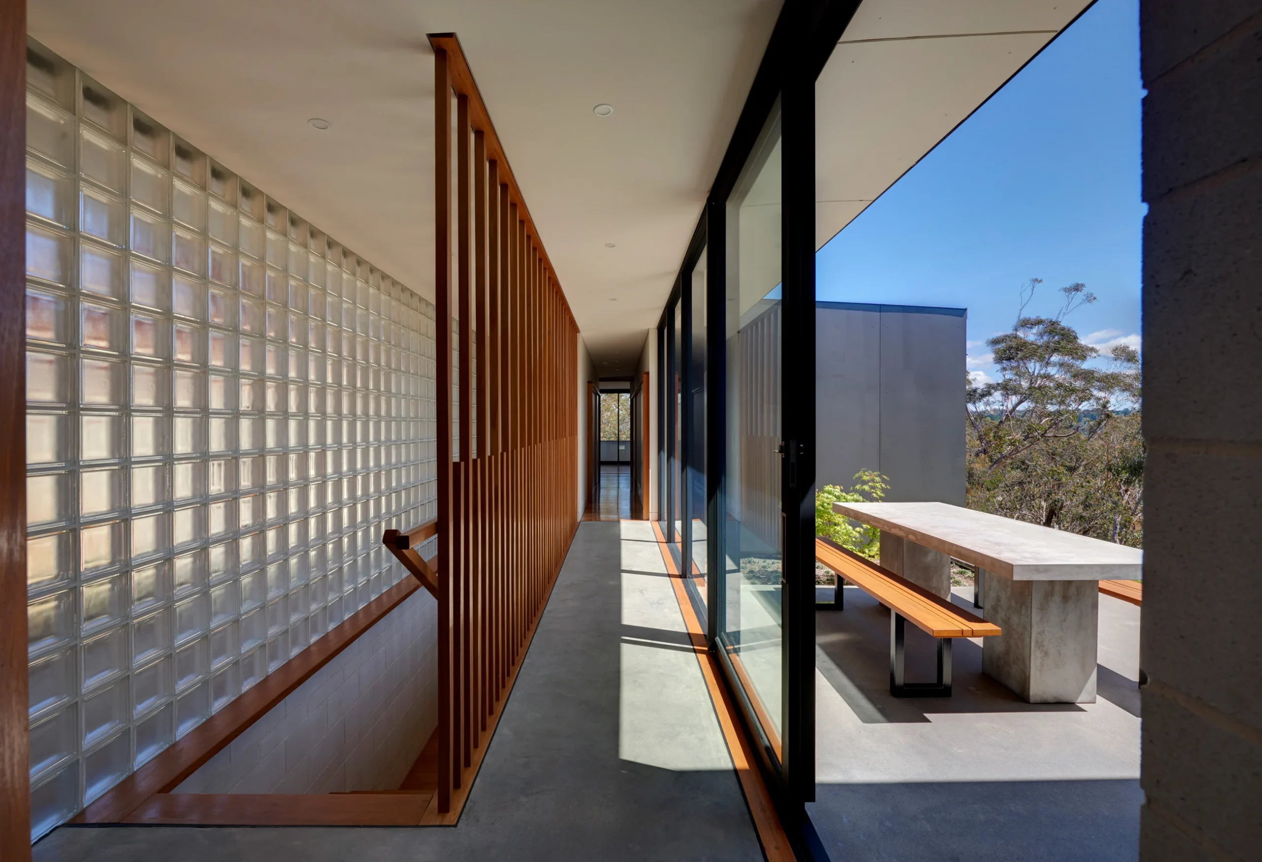 Interior with a view of the exterior patio of a bushfire-proof property in Leura, Blue Mountains designed by Northern Beaches architects Markham Lee.